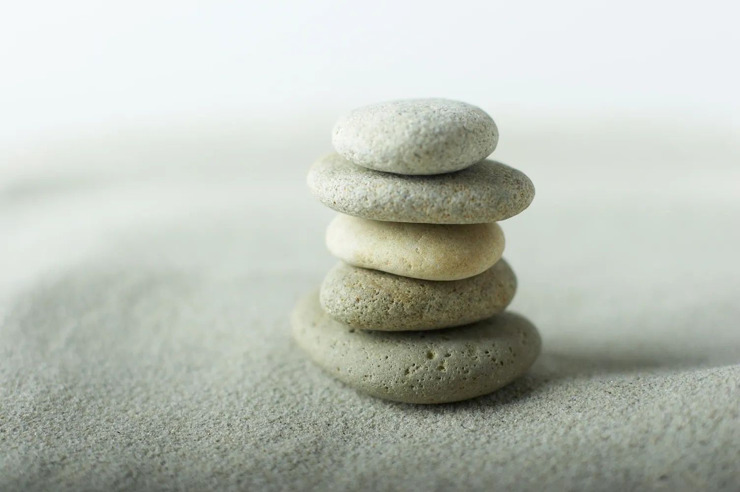 A stack of zen pebbles on raked sand
