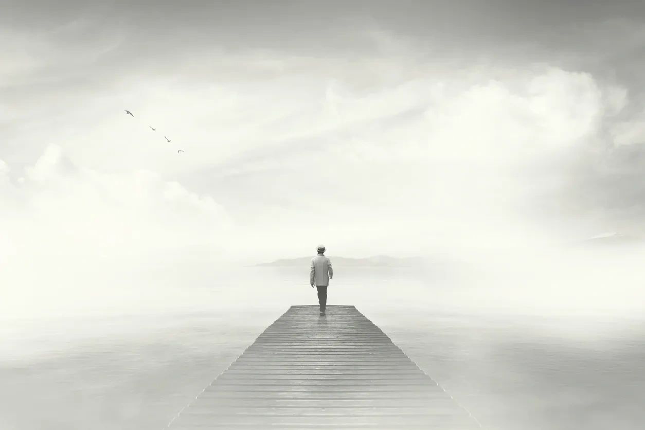 Figure walking down a wooden pier in mist